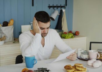 Man sitting at table reading papers with breakfast