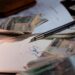 Pen and money scattered on documents